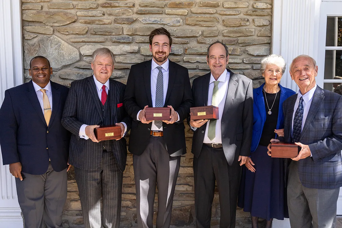 Houghton president Wayne Lewis standing with alumni award recipients.