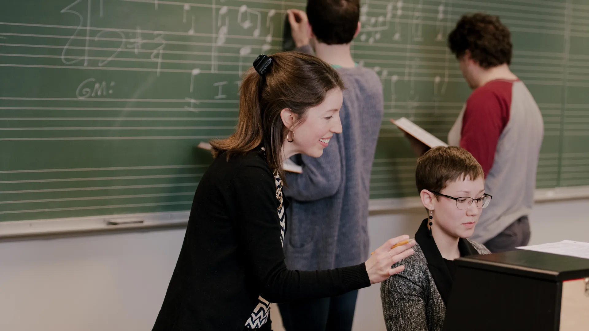 Houghton University Music Teacher in the classroom helping a student with the piano.