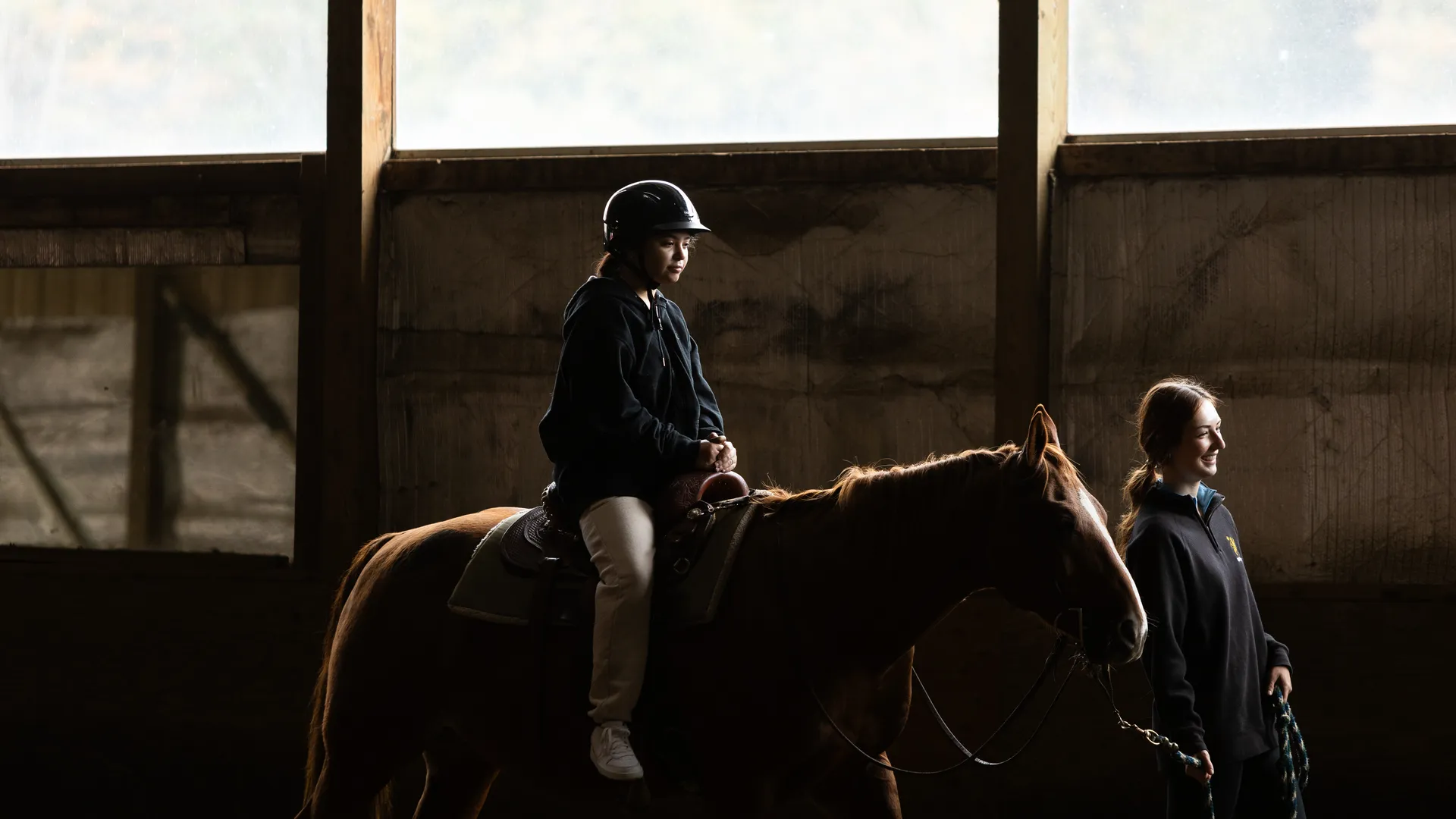 student walking a horse with a rider