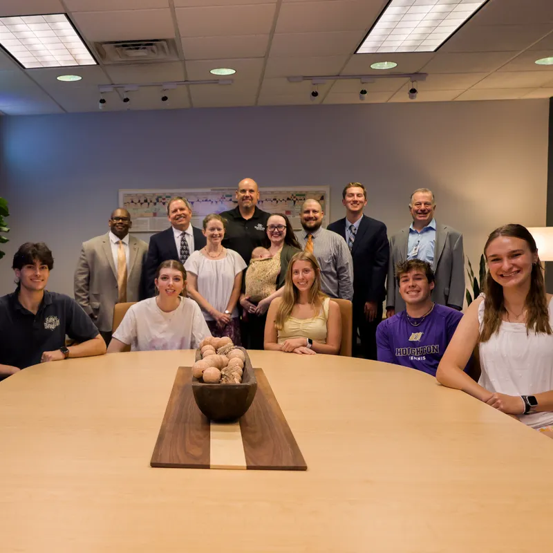 Students and faculty smiling around a table